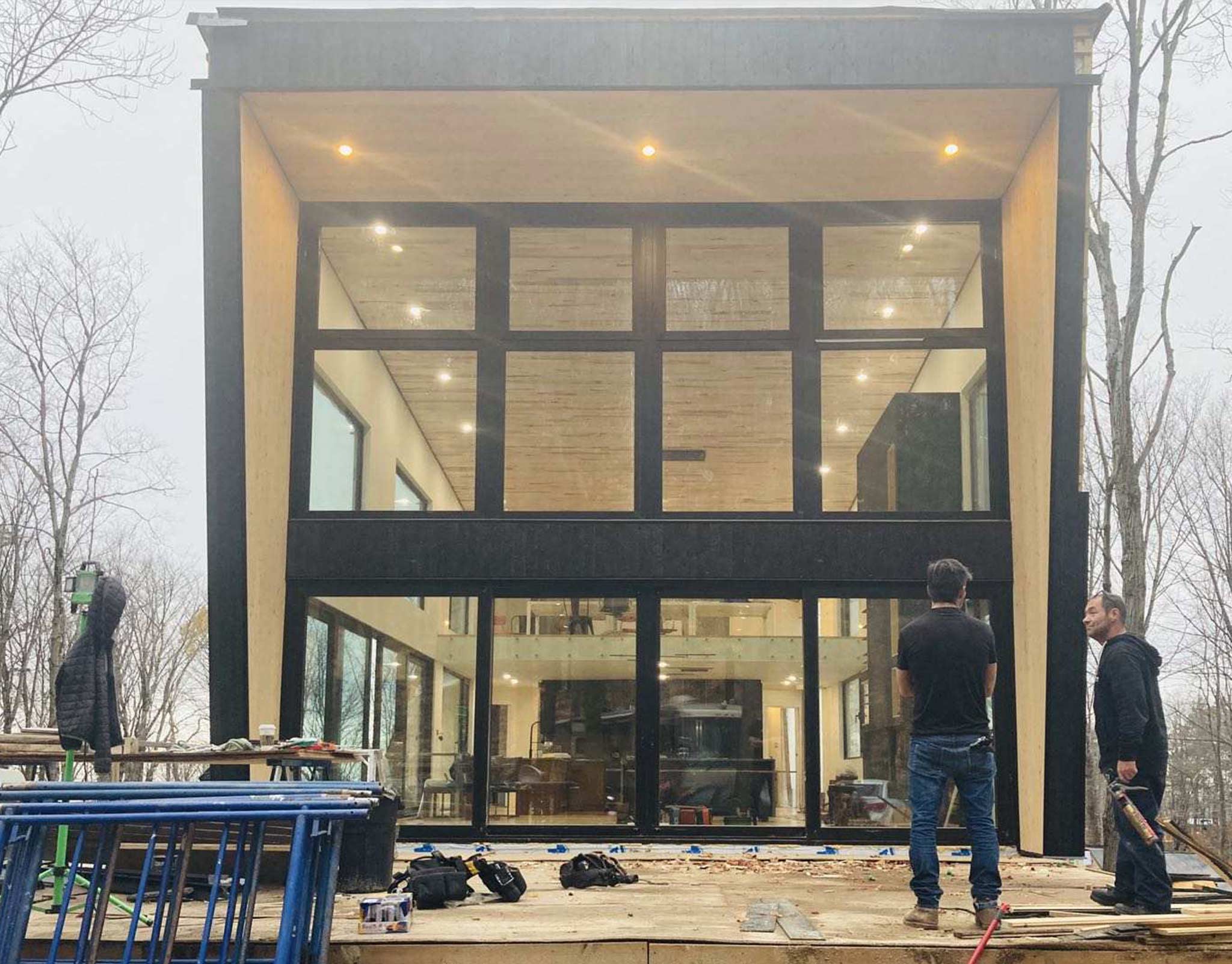 Double-height glazed storefront under construction with workers on the sidewalk in front