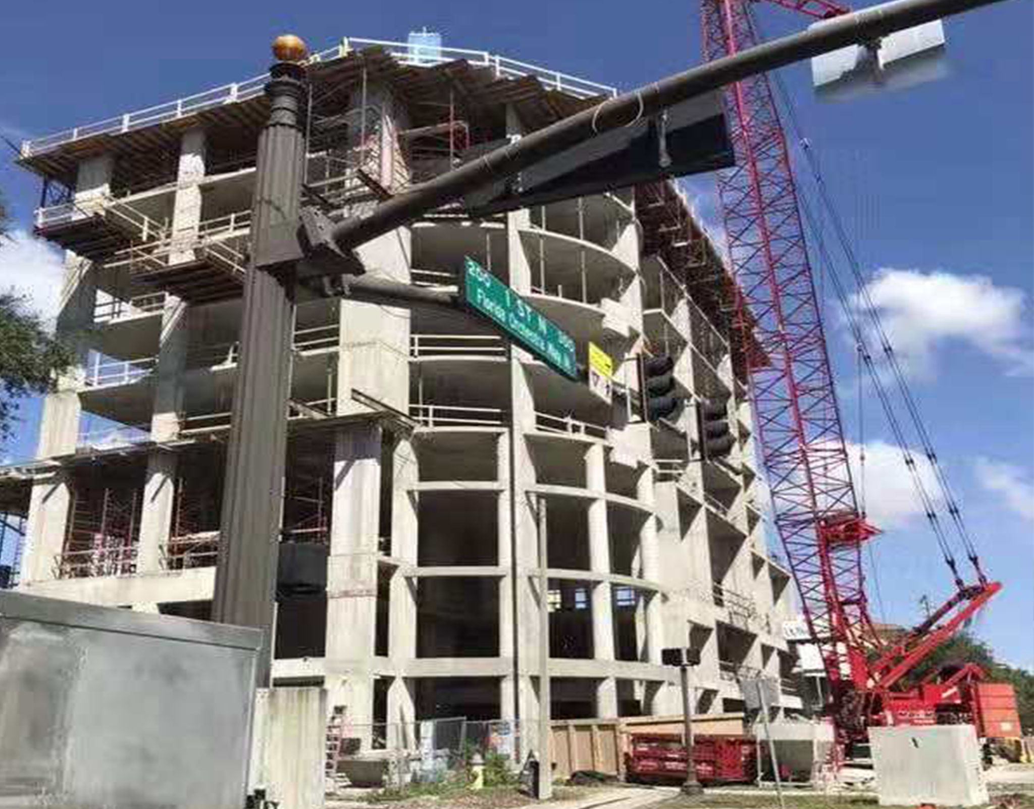 Concrete frame of a residential building under construction with a tower crane above the podium