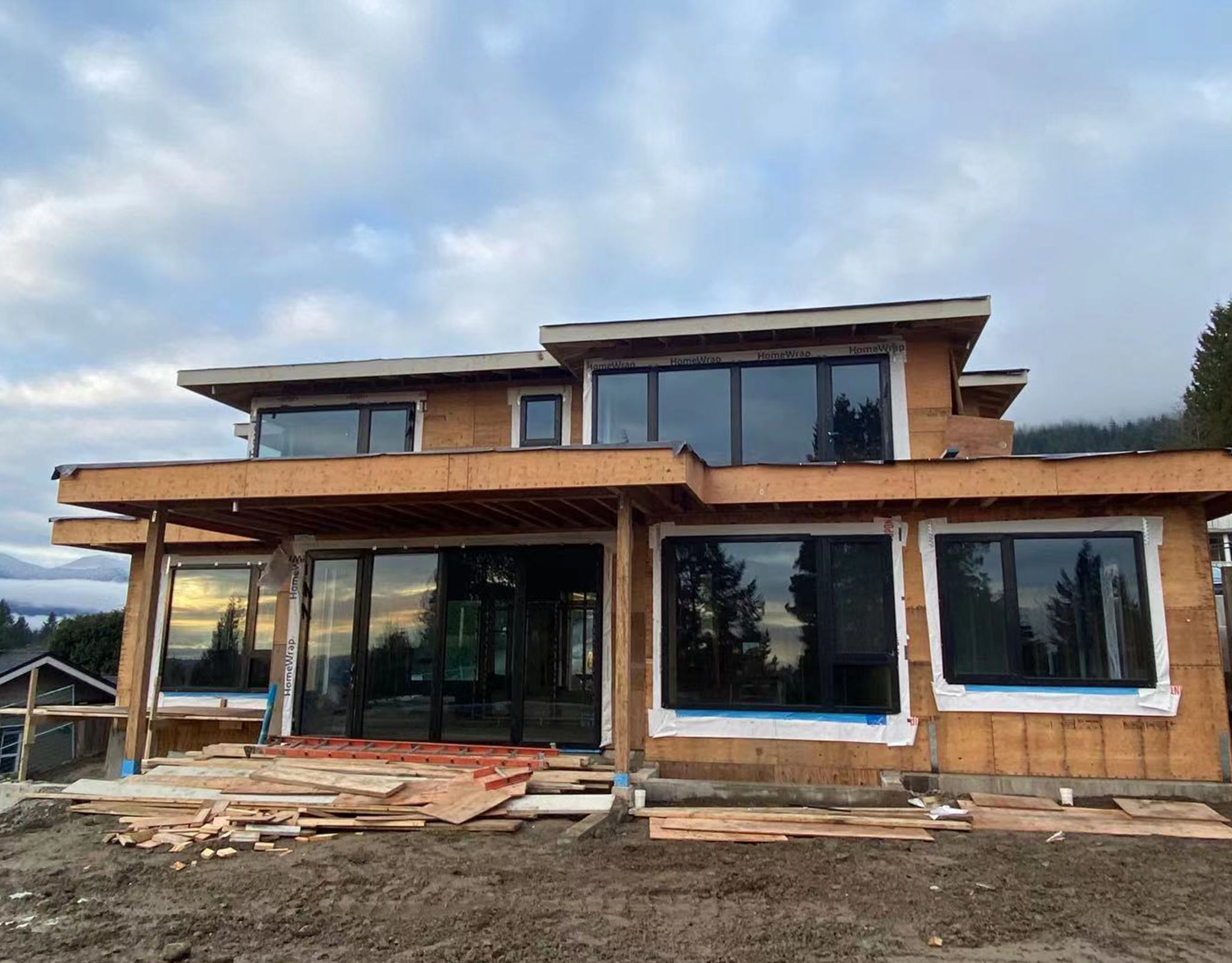 Timber-clad commercial building under construction with large fixed windows set into the facade