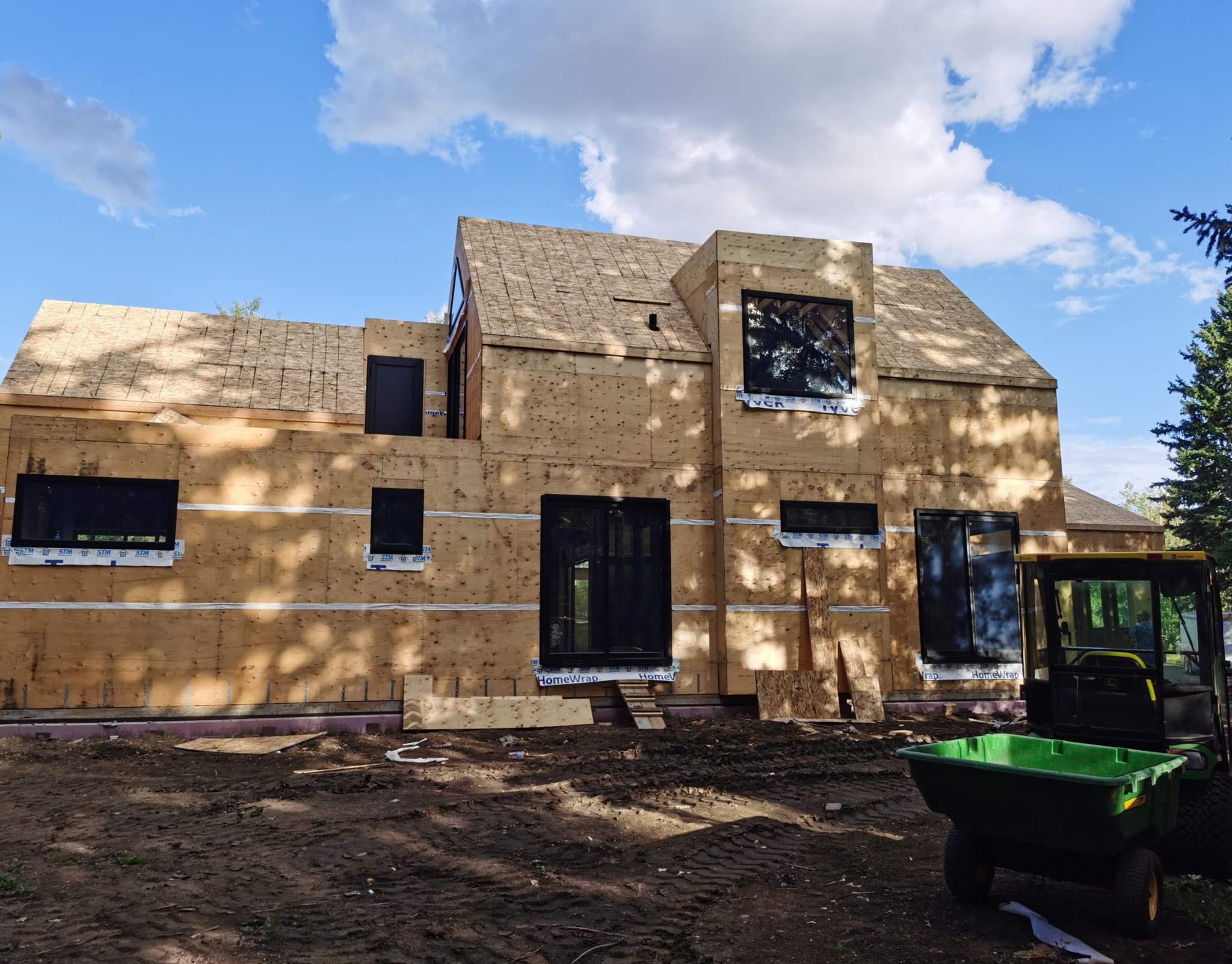 Wood-framed residence under construction with black aluminum window openings installed