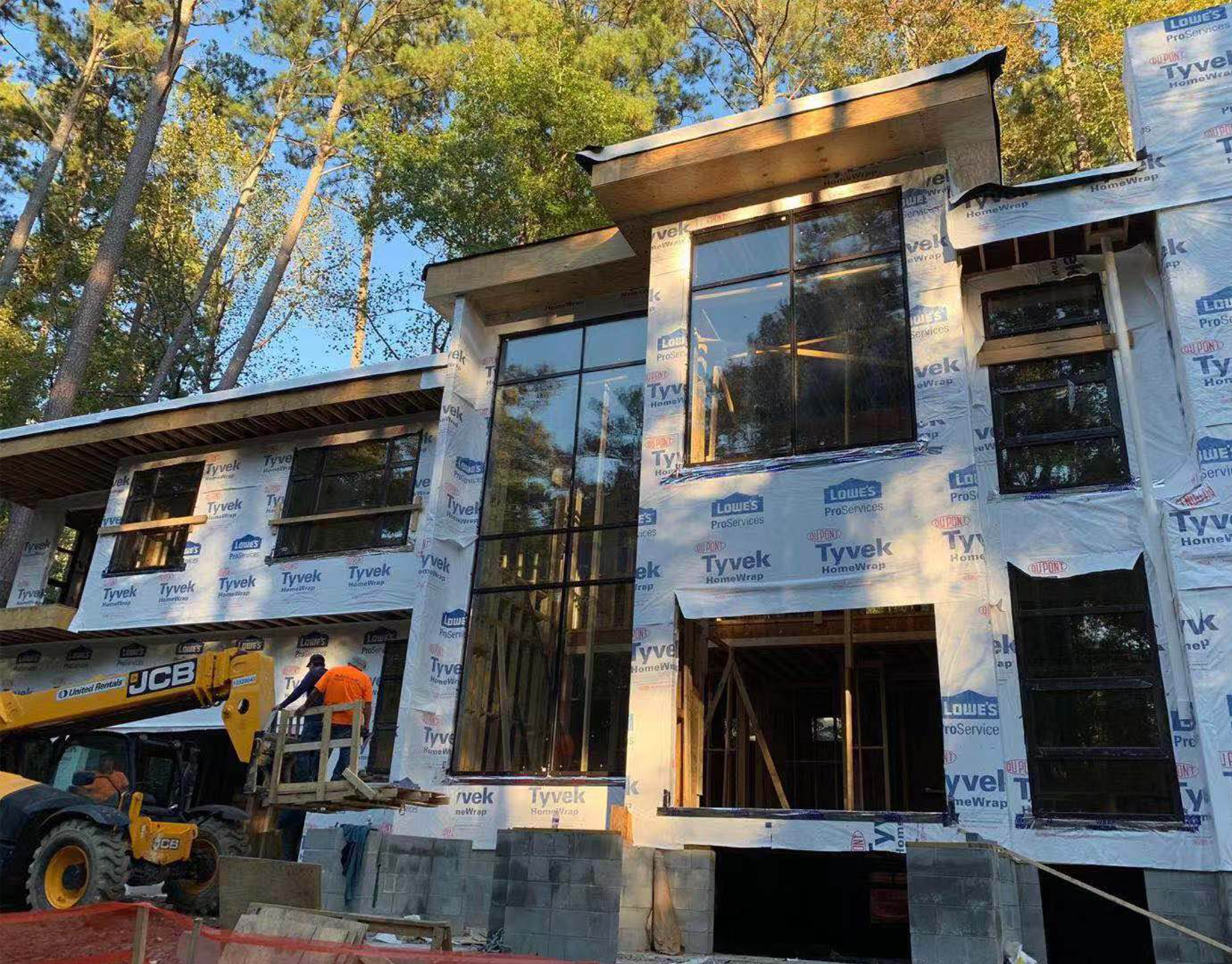 Glazing installation in progress on a framed building with a telehandler lifting units into place