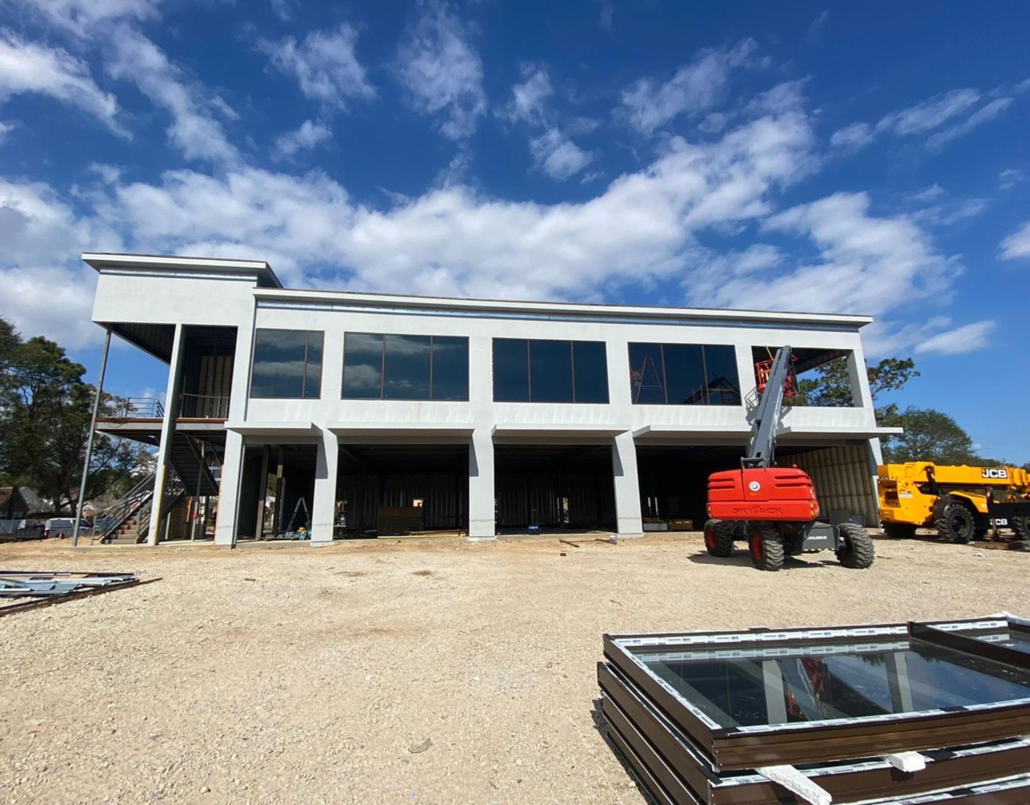 Two-storey commercial building under construction with storefront glazing installed along the elevation